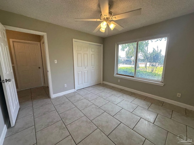 unfurnished bedroom featuring ceiling fan, light tile patterned floors, a closet, and a textured ceiling