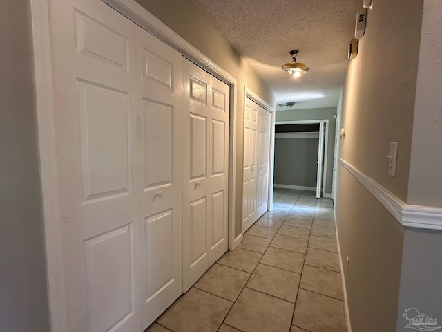 hall featuring a textured ceiling and light tile patterned floors