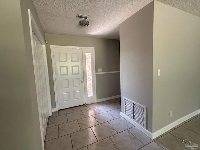 entryway with light tile patterned floors and a textured ceiling