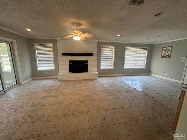 unfurnished living room featuring crown molding, a brick fireplace, a textured ceiling, and a healthy amount of sunlight