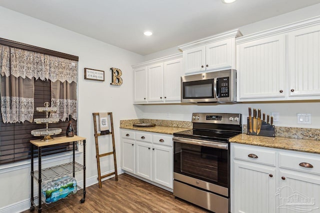 kitchen featuring white cabinets, stainless steel appliances, light stone counters, and dark wood-type flooring