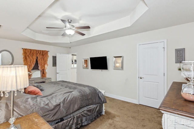 carpeted bedroom featuring a tray ceiling and ceiling fan