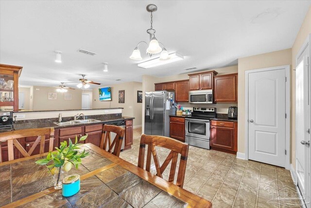 kitchen featuring sink, hanging light fixtures, kitchen peninsula, ceiling fan with notable chandelier, and appliances with stainless steel finishes