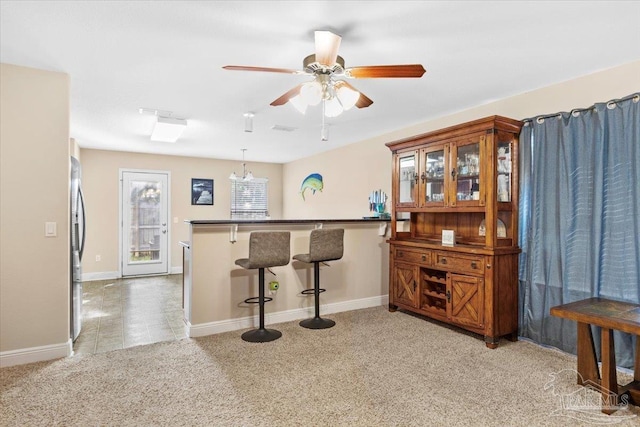 kitchen with a breakfast bar area, kitchen peninsula, light colored carpet, and pendant lighting