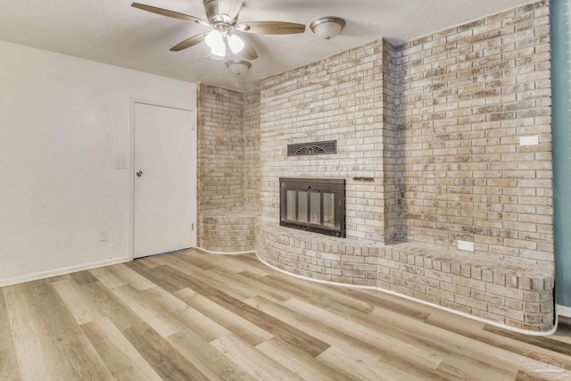 unfurnished living room with a fireplace, wood finished floors, baseboards, and ceiling fan