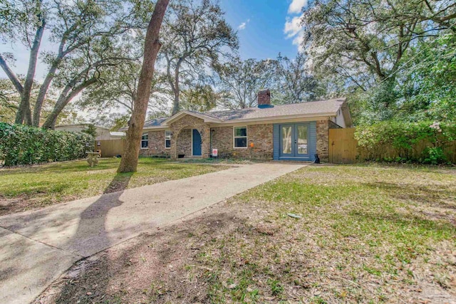 ranch-style home featuring fence, a chimney, a front lawn, concrete driveway, and stone siding