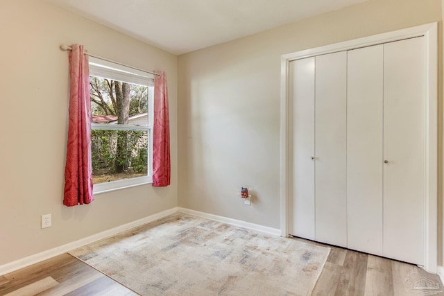 unfurnished bedroom with baseboards, light wood-type flooring, and a closet