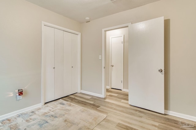 unfurnished bedroom featuring a closet, light wood-style flooring, and baseboards