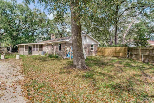 exterior space with fence, central AC, a chimney, and a sunroom