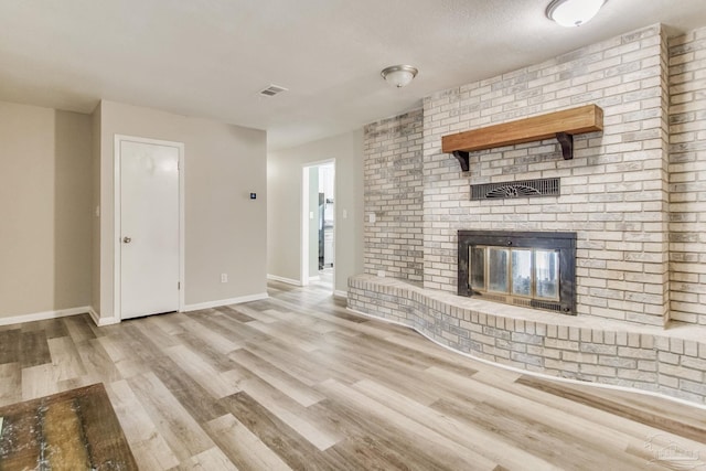 unfurnished living room featuring a fireplace, wood finished floors, visible vents, and baseboards