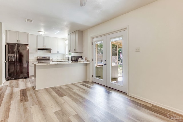 kitchen featuring electric stove, under cabinet range hood, french doors, a peninsula, and black refrigerator with ice dispenser