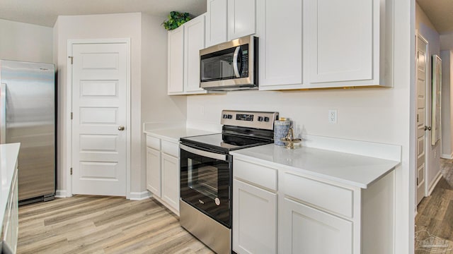 kitchen with white cabinetry, appliances with stainless steel finishes, and light hardwood / wood-style floors