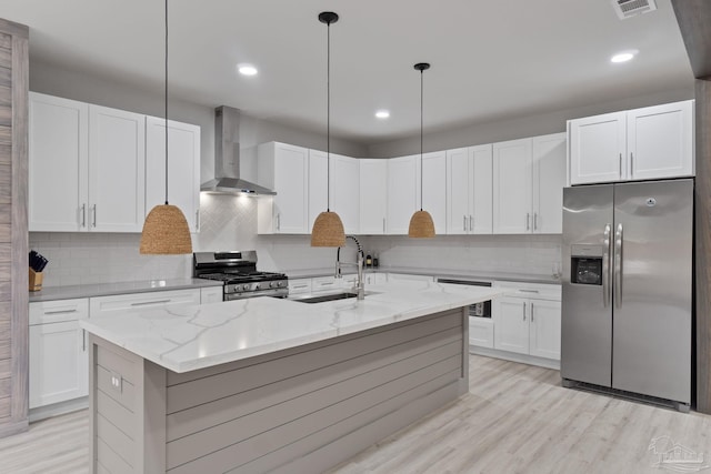 kitchen with pendant lighting, white cabinetry, wall chimney range hood, and appliances with stainless steel finishes