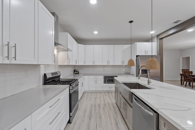 kitchen featuring white cabinets, sink, stainless steel appliances, and hanging light fixtures