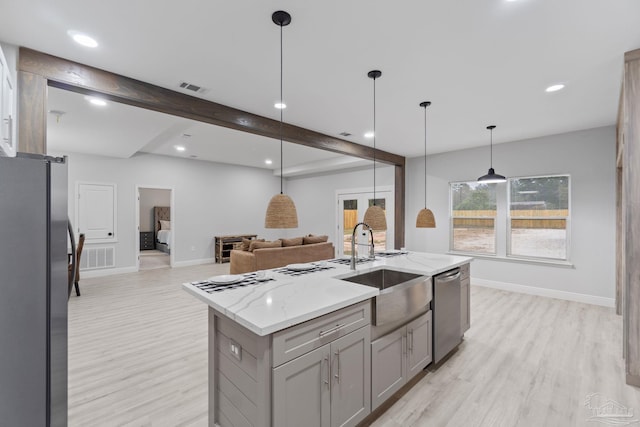 kitchen with stainless steel appliances, a kitchen island with sink, sink, beamed ceiling, and hanging light fixtures