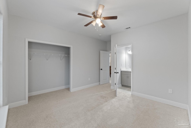 unfurnished bedroom featuring light carpet, a closet, ceiling fan, and ensuite bathroom