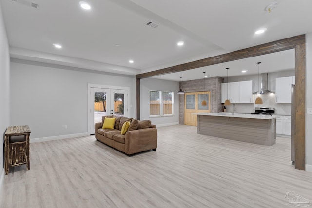 living room with beam ceiling, sink, french doors, and light wood-type flooring