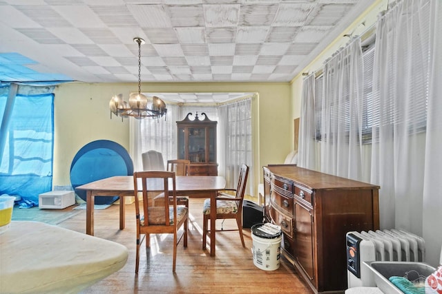 dining space with radiator heating unit, a notable chandelier, and light hardwood / wood-style floors