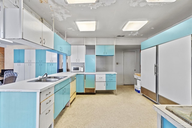 kitchen with dishwashing machine, sink, blue cabinetry, white cabinetry, and a kitchen island