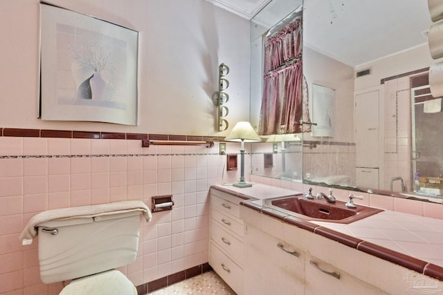 bathroom featuring tile walls, vanity, crown molding, and toilet