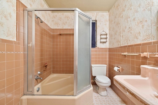 bathroom featuring enclosed tub / shower combo, tile patterned floors, toilet, and tile walls