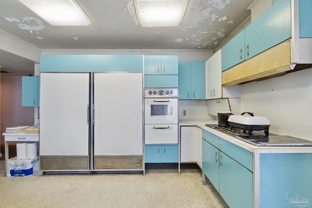 kitchen featuring fridge, oven, stainless steel gas stovetop, and blue cabinetry