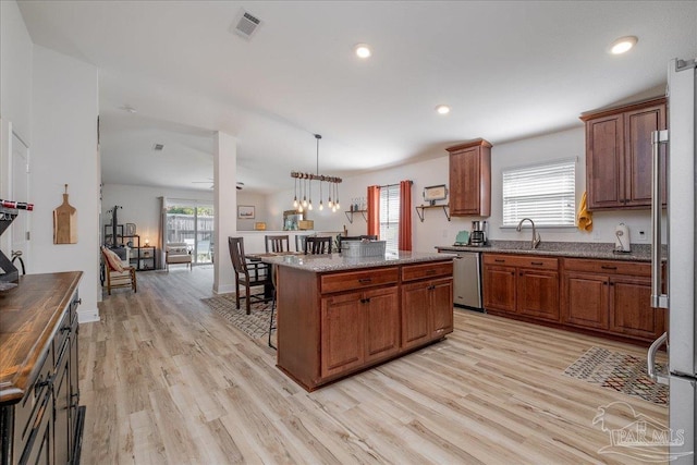 kitchen with decorative light fixtures, a kitchen breakfast bar, a center island, stainless steel appliances, and light hardwood / wood-style flooring