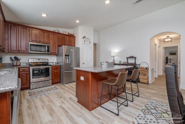 kitchen featuring lofted ceiling, a breakfast bar, a center island, light wood-type flooring, and stainless steel appliances