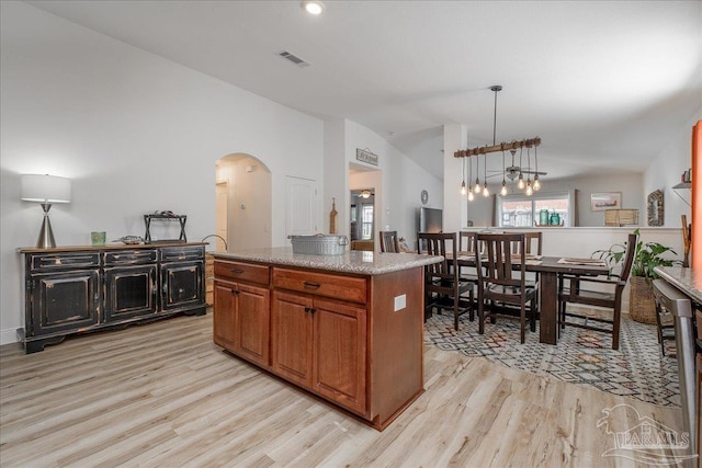 kitchen featuring lofted ceiling, decorative light fixtures, a center island, and light wood-type flooring