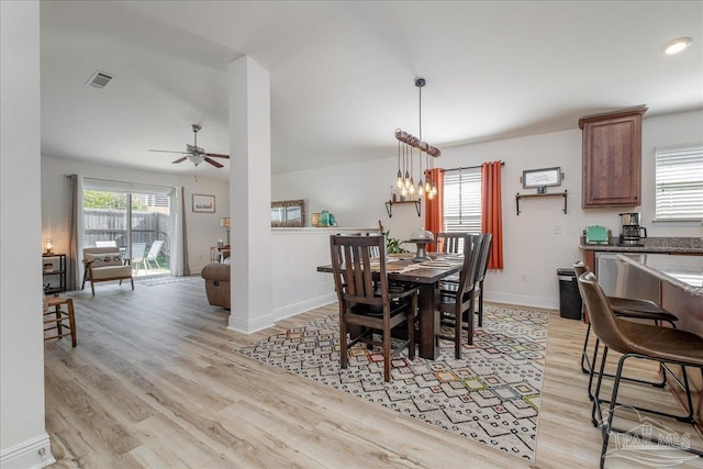 dining space with ceiling fan with notable chandelier and light hardwood / wood-style floors