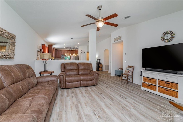 living room featuring ceiling fan with notable chandelier and light hardwood / wood-style floors