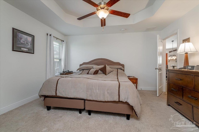 bedroom with a tray ceiling, light colored carpet, and ceiling fan