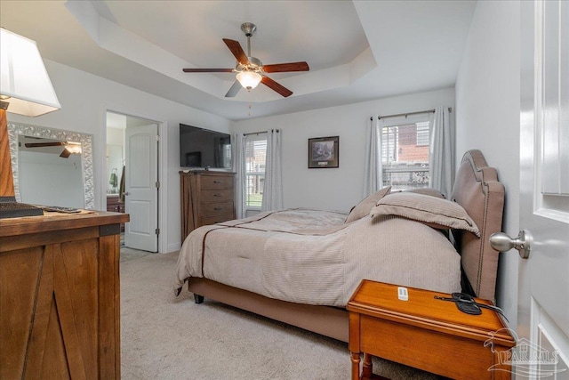 carpeted bedroom with ceiling fan, a raised ceiling, and multiple windows