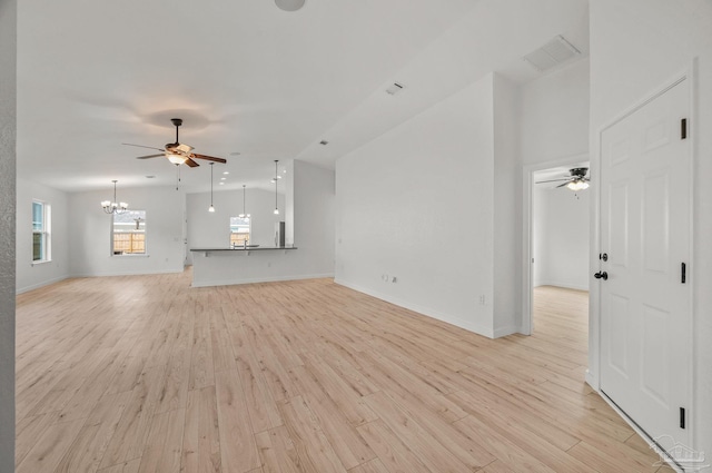unfurnished living room with visible vents, light wood-style flooring, ceiling fan with notable chandelier, and baseboards
