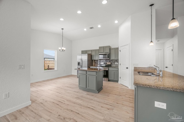 kitchen with an inviting chandelier, a center island, a sink, stone counters, and stainless steel appliances