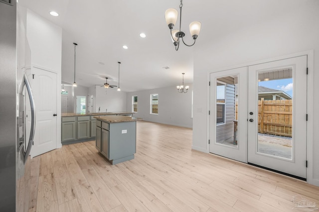 kitchen with light wood-style floors, french doors, ceiling fan with notable chandelier, freestanding refrigerator, and open floor plan