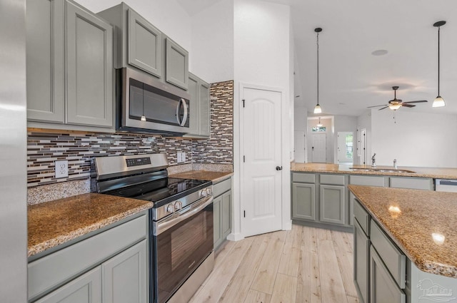 kitchen featuring appliances with stainless steel finishes, a sink, gray cabinets, light wood-style flooring, and a ceiling fan
