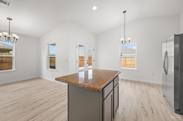 kitchen featuring freestanding refrigerator, vaulted ceiling, an inviting chandelier, and visible vents