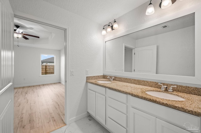 full bath featuring visible vents, a sink, baseboards, and a textured wall