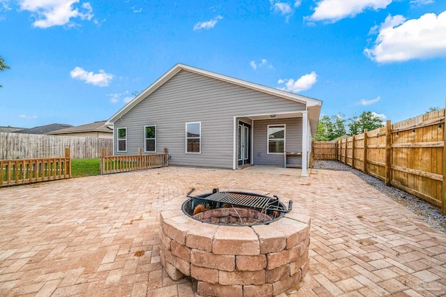 rear view of house with a fenced backyard, a fire pit, and a patio area