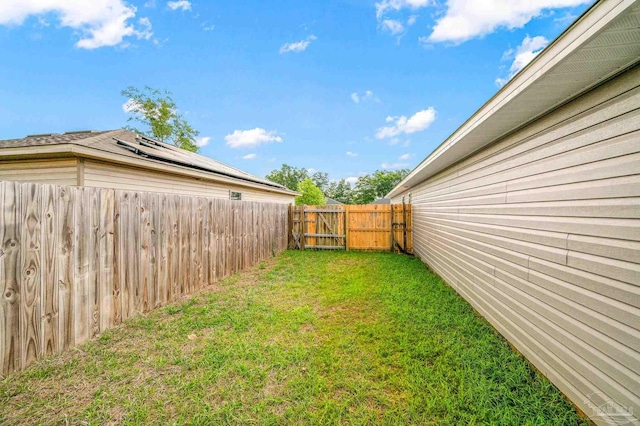 view of yard with a fenced backyard and a gate