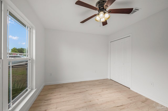 unfurnished bedroom featuring a closet, visible vents, wood finished floors, baseboards, and ceiling fan