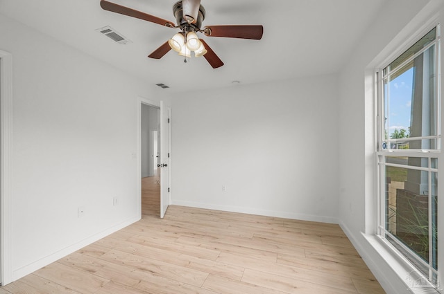 spare room featuring visible vents, a ceiling fan, light wood-style flooring, and baseboards