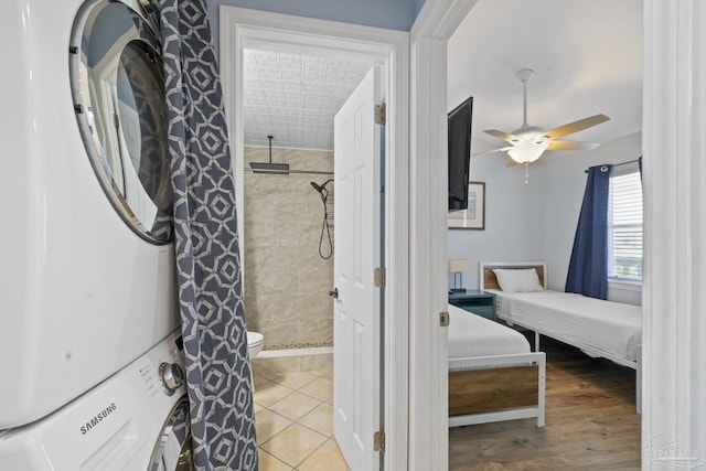 interior space featuring light tile patterned flooring, ceiling fan, and stacked washing maching and dryer