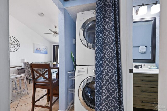 laundry room featuring stacked washing maching and dryer, sink, light tile patterned flooring, and ceiling fan