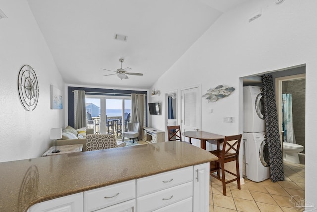 kitchen featuring stacked washer / dryer, vaulted ceiling, and white cabinets