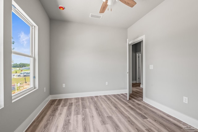 spare room with light wood-style flooring, visible vents, a ceiling fan, and baseboards