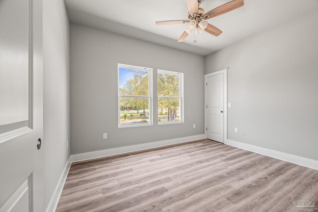 spare room with baseboards, a ceiling fan, and light wood-style floors