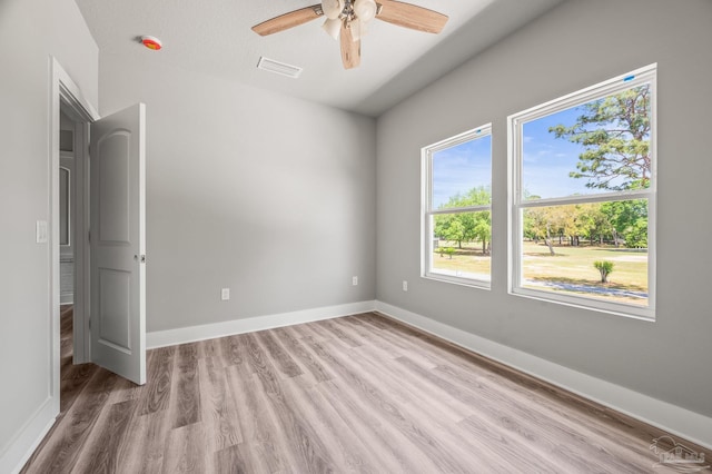 empty room featuring baseboards, a ceiling fan, visible vents, and light wood-style floors