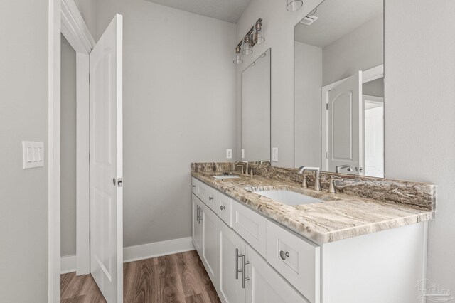 bathroom featuring visible vents, wood finished floors, a sink, and double vanity